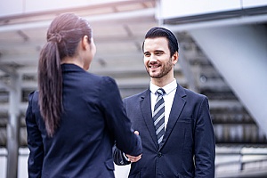 an employee shaking hands with his manager who holds an employment visa