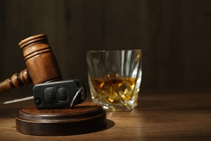 car key gavel near glass of alcohol on wooden table needing to removing dui from record