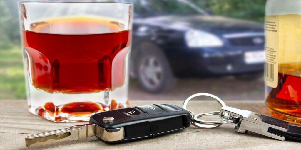 car keys with a glass of liquor on the background of the car