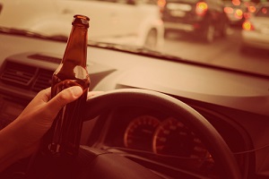 man drink beer while driving car