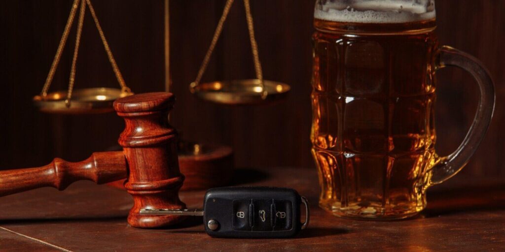 glass of beer car keys and wooden gavel in a notary office
