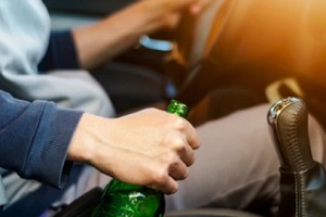 man driving while alochol bottle in hand
