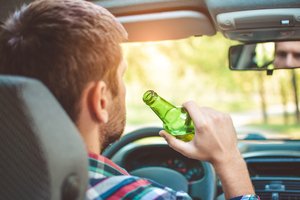 Man drinking alcohol inside his car