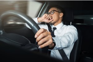 A man with a tie is driving a car and showing tense expressions on his face