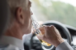 aged man drinking while driving the car