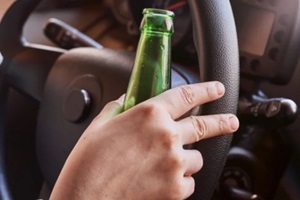 unrecognizable female drinking beer while driving car